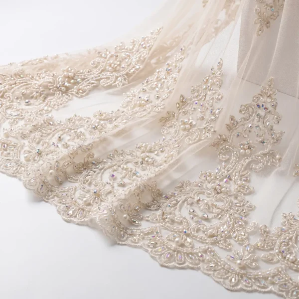 Ivory pearl and crystal hand beaded lace fabric with ornate floral embroidery and scalloped border.