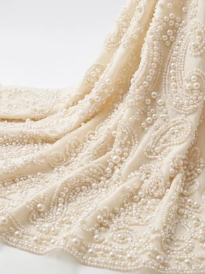 Paisley Pearl Beaded Fabric Ivory pearl beaded fabric with intricate paisley motifs and graduated pearl embellishments for bridal and couture fashion.