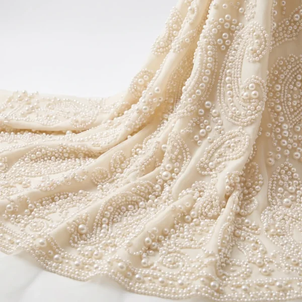 Paisley Pearl Beaded Fabric Ivory pearl beaded fabric with intricate paisley motifs and graduated pearl embellishments for bridal and couture fashion.