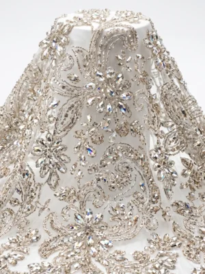 Silver Floral Crystal Beaded Fabric Silver crystal beaded fabric with floral motifs, clear faceted stones and swirling hand embellished vine patterns.