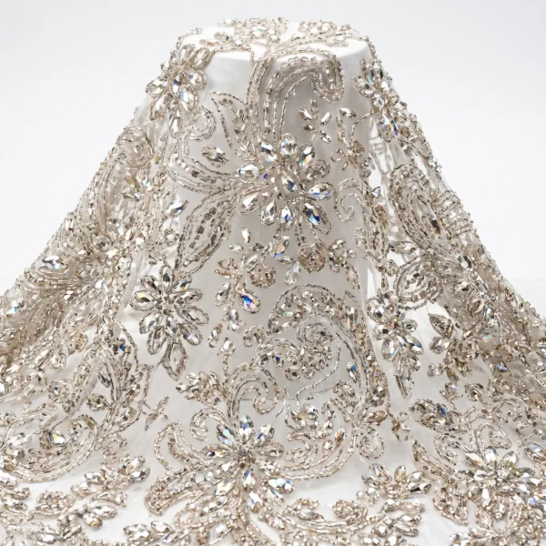 Silver Floral Crystal Beaded Fabric Silver crystal beaded fabric with floral motifs, clear faceted stones and swirling hand embellished vine patterns.